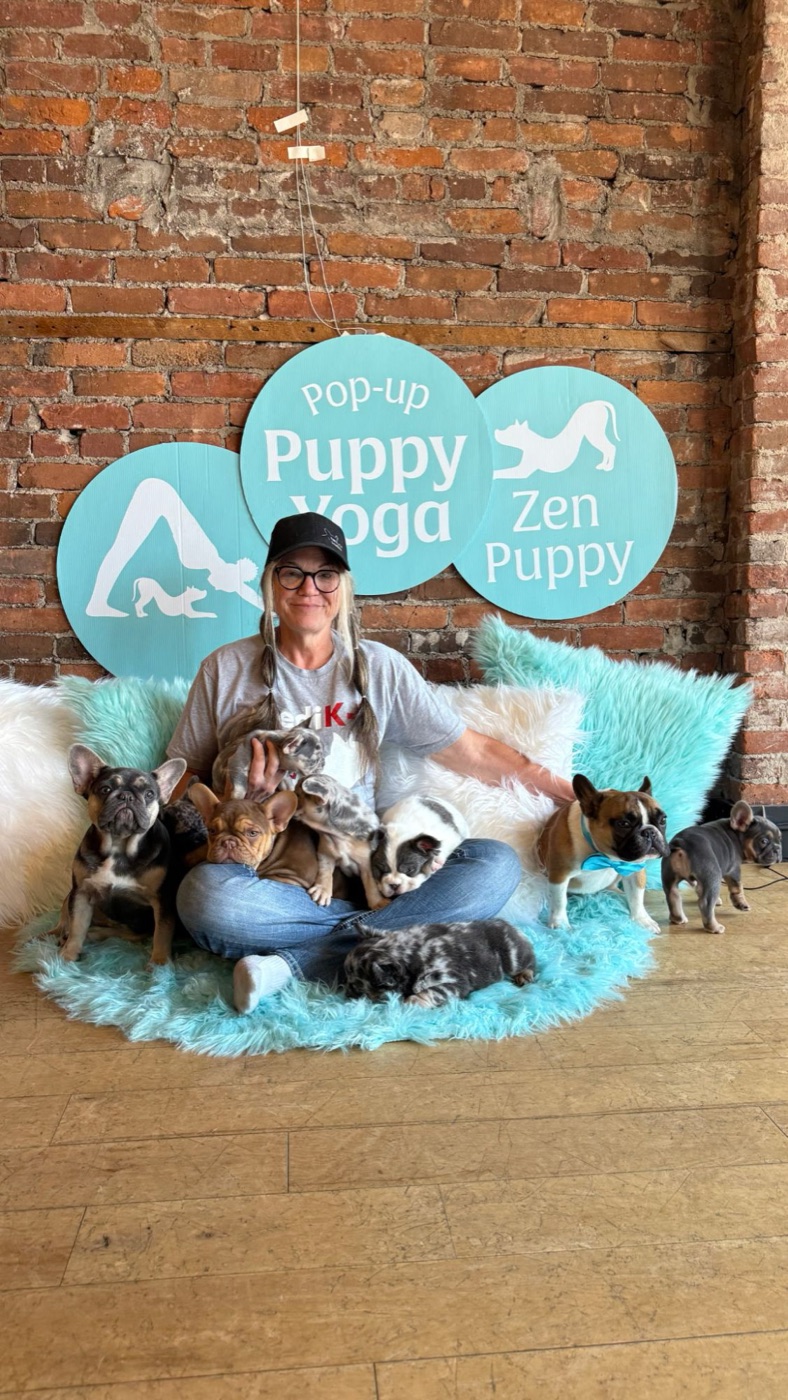 Paula Busch of Forever Frenchies surrounded by French Bulldog puppies at a Pop-up Puppy Yoga event